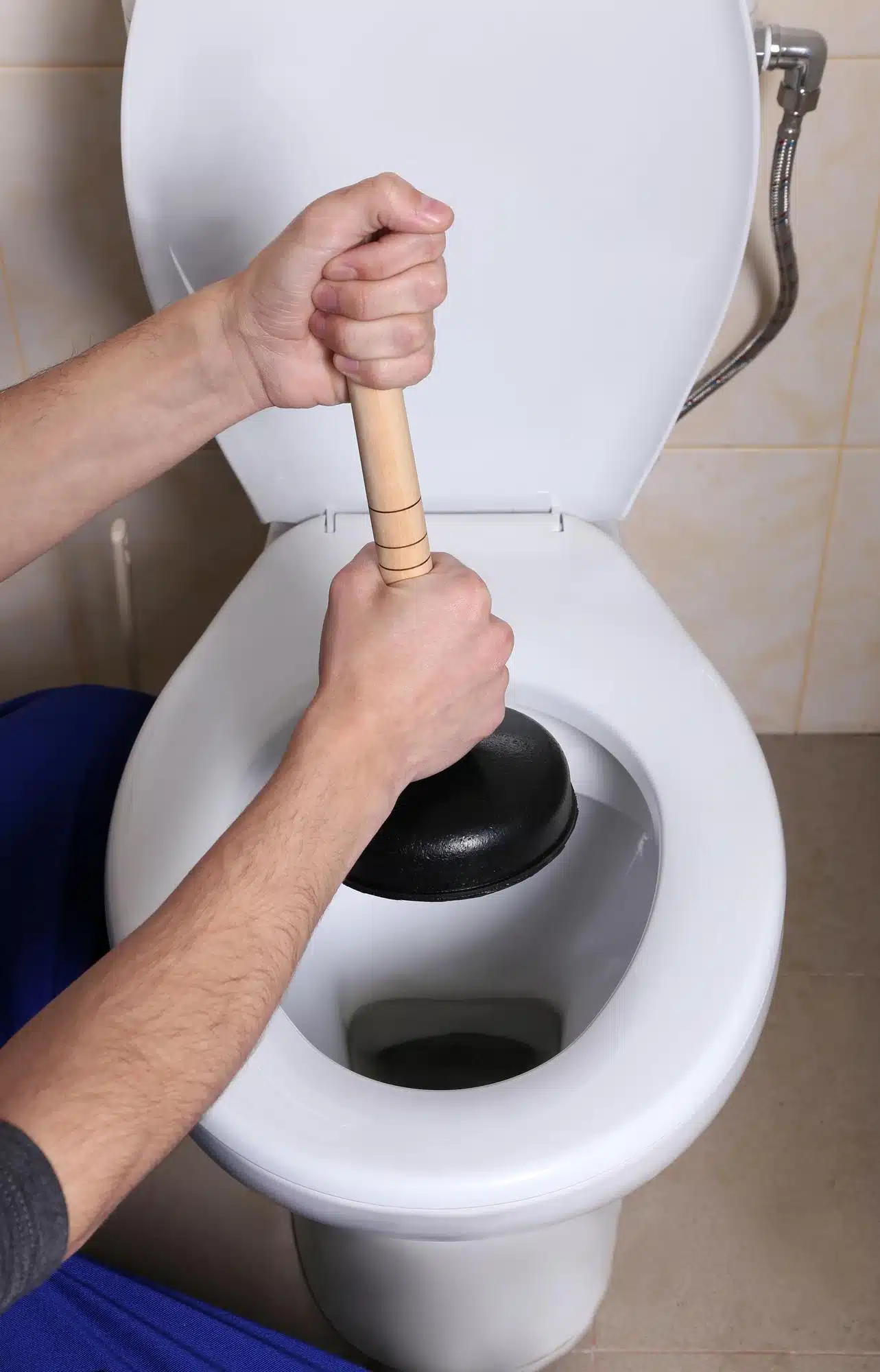 Plumber repairing toilet with hand plunger